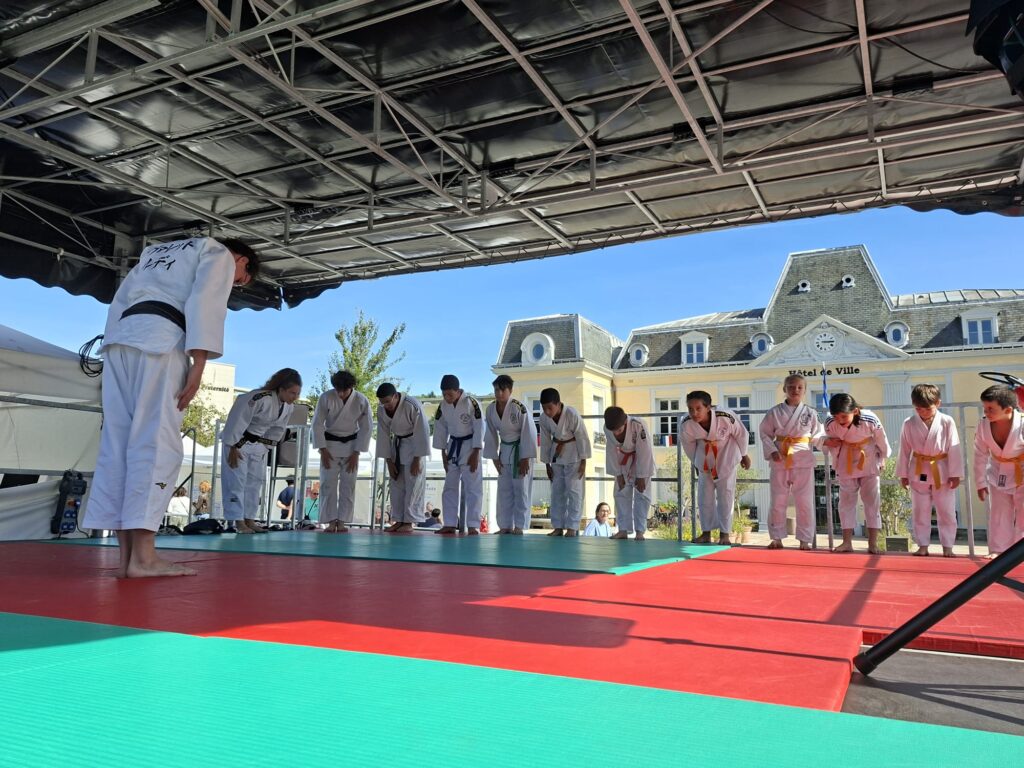 Démonstration de judo par les judokas du club EG Judo lors du Forum des Associations de Gagny, avec Ruddy Vallet orchestrant la prestation sur le podium, entouré des participants et des parents venus soutenir le club